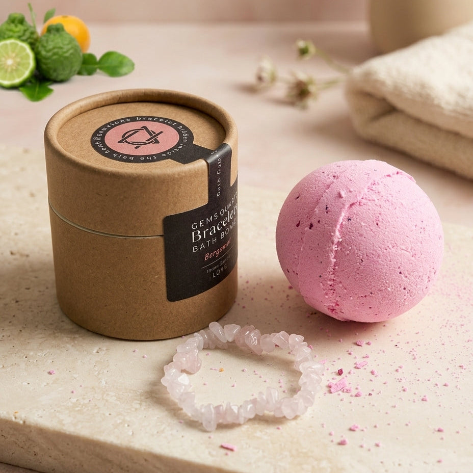 A pink bath bomb and its kraft paper packaging container on a stone surface, with a translucent crystal bracelet in front and small citrus and flowers as styled props.
