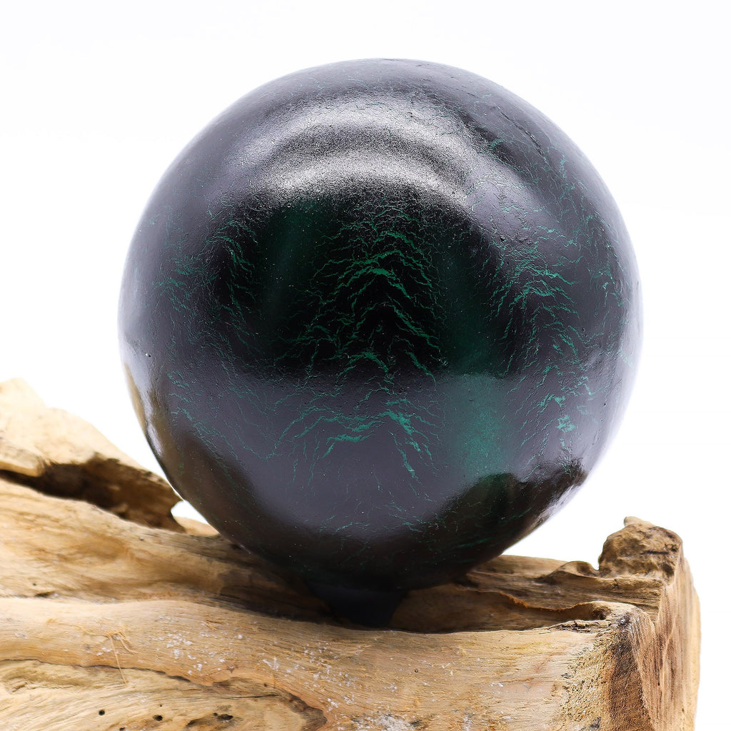 Black and green crystal ball on a wooden surface with a white background