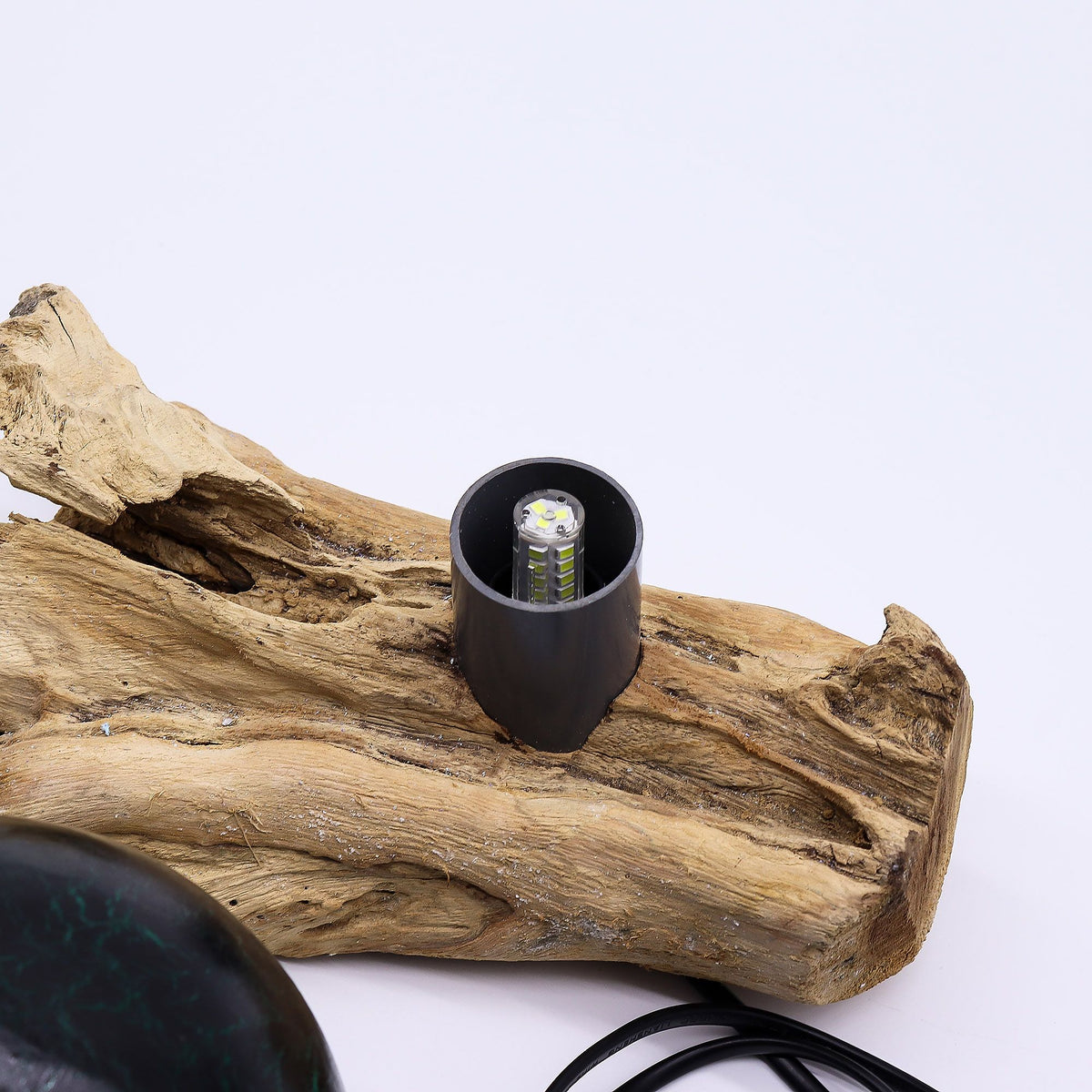 Black lampshade on a piece of driftwood with a white background