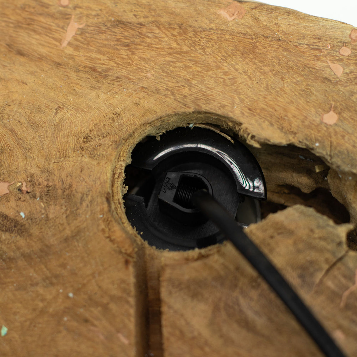 Close-up of a metal rod being inserted into a wooden hole.