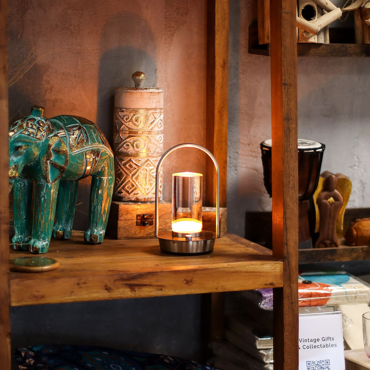 Decorative items including a teal elephant figurine and a lit candle on a wooden shelf.
