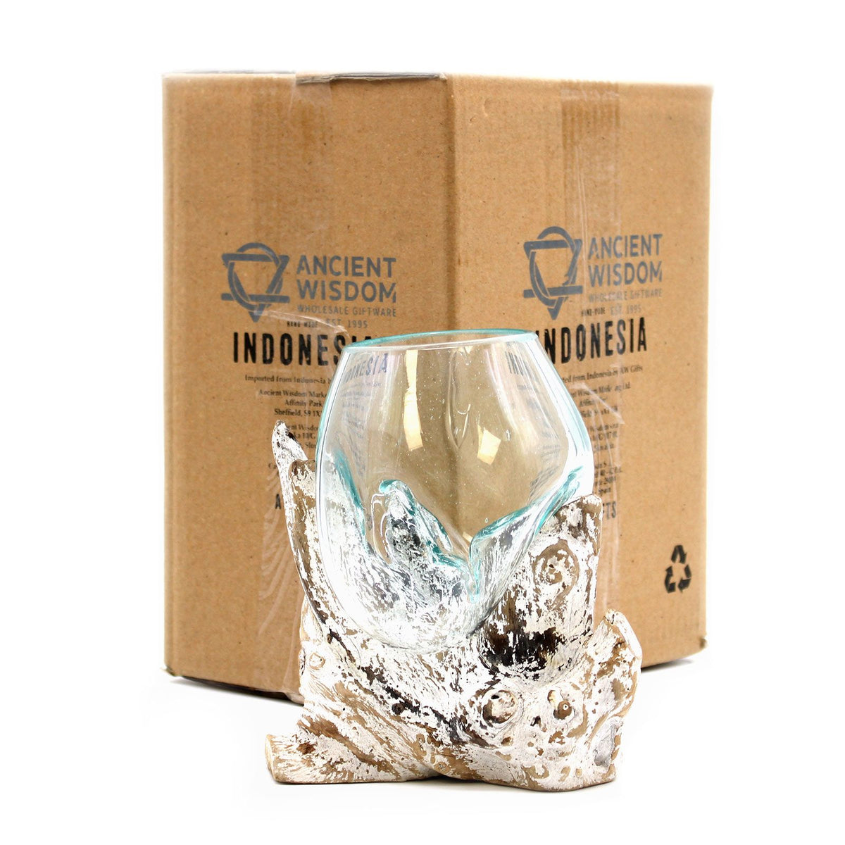 Glass vase with natural base design in front of a cardboard box labeled 'Ancient Wisdom Indonesia'.