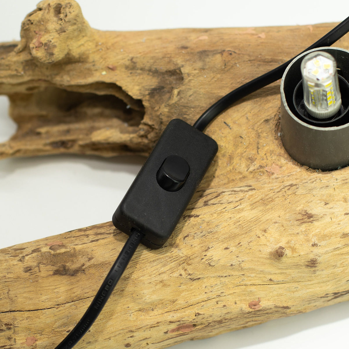 Black light switch and cable on a piece of driftwood